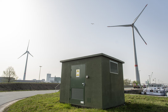 Elektriciteitscabine van Fluvius in Antwerpen Haven met op de achtergrond 2 windmolens