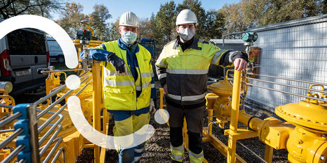 Twee Fluvius-technici op een werf glimlachen voor de foto.